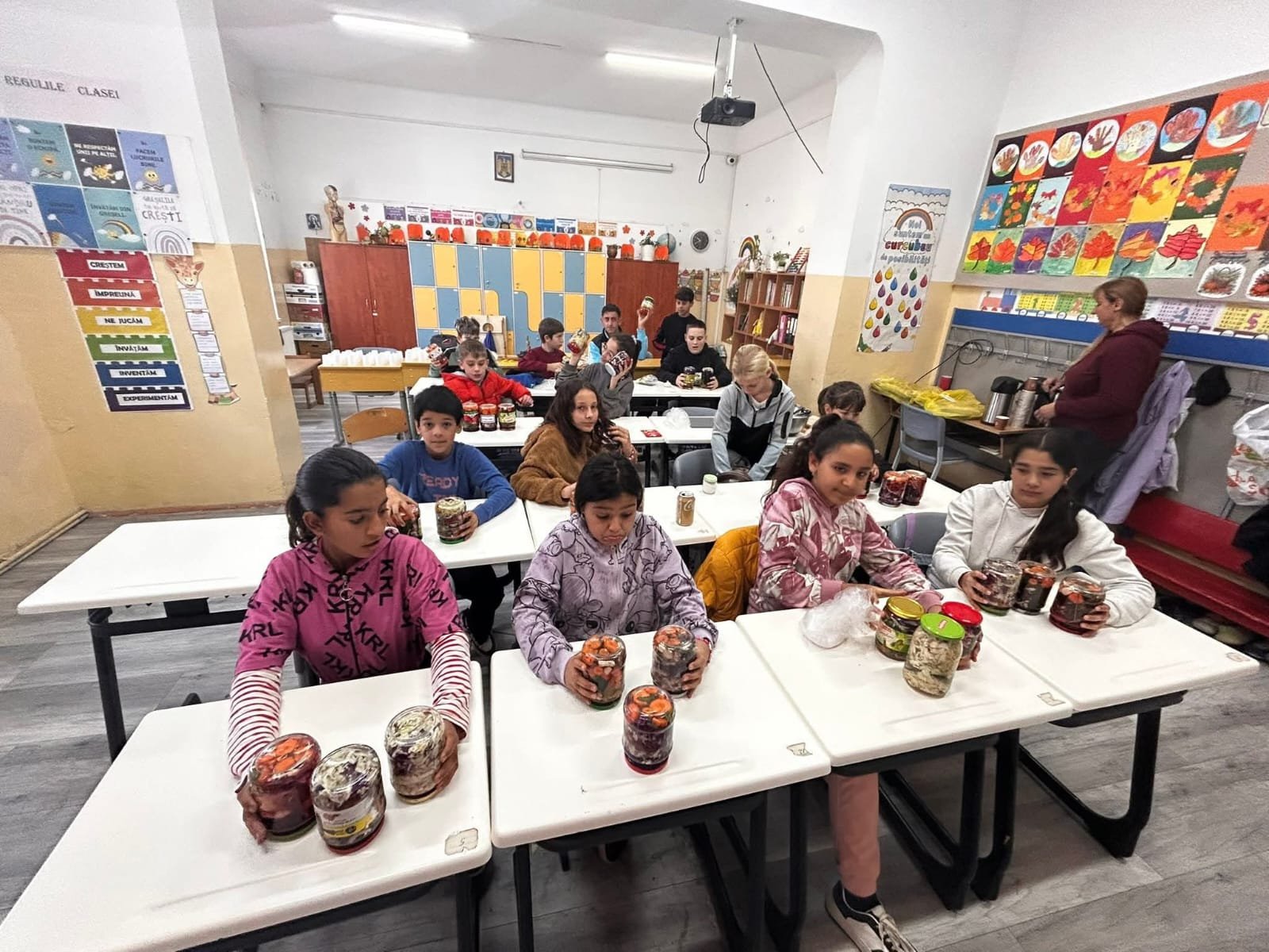Elevi la bănci, cu borcanele de murături pregătite în cadrul proiectului „Culorile toamnei – Atelier de creație și tradiție”.
