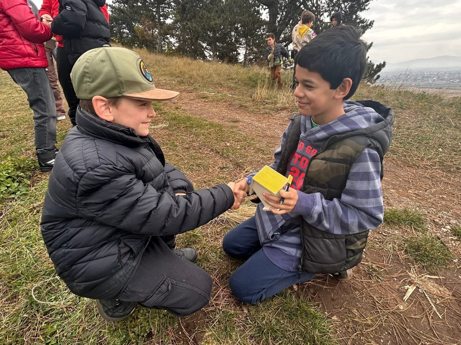 Doi băieți lucrând împreună într-un joc educativ în cadrul proiectului Recunoștință în Natură pe Dealul Lempes.