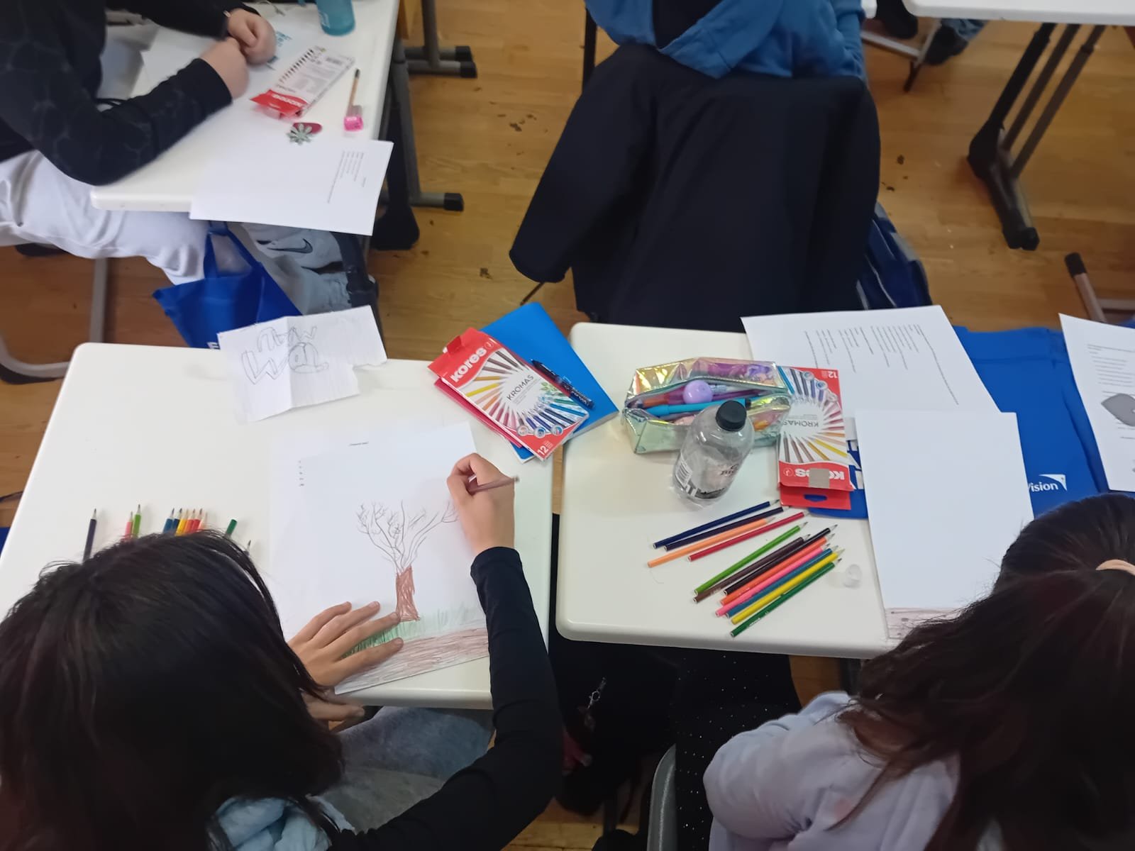 Vedere de sus cu elevi care lucrează la desene și fișe First Aid Arts în cadrul lecției despre emoții și dezvoltare personală