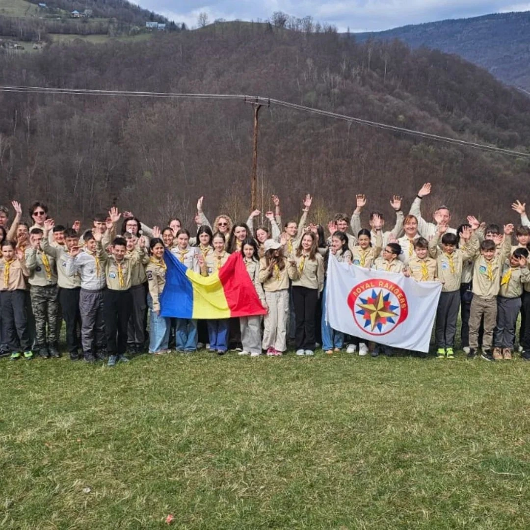 Cercetașii Royal Rangers cu steagurile României și ale organizației, pe un deal